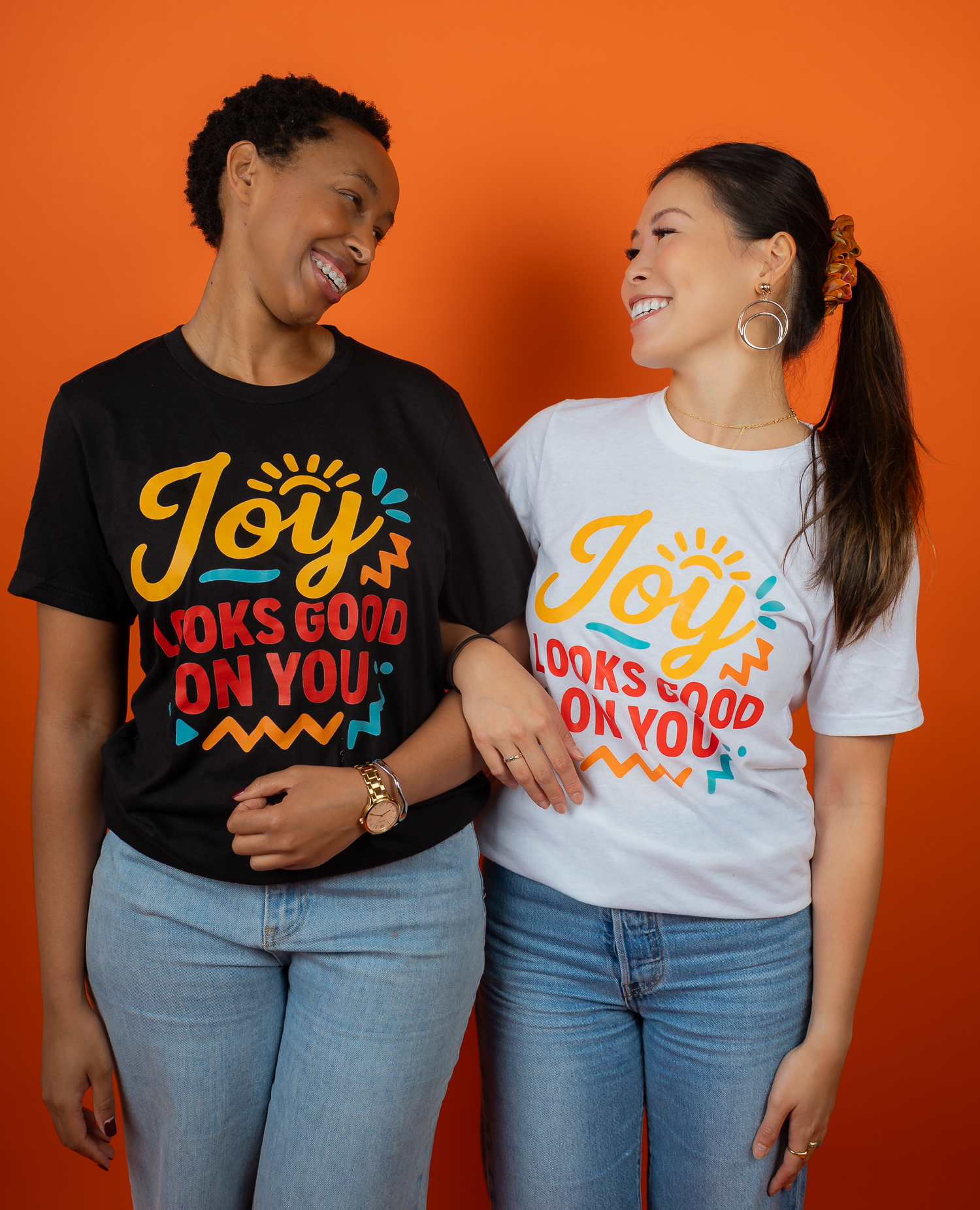 Three women dancing in their Joy Looks Good on You Crewnecks